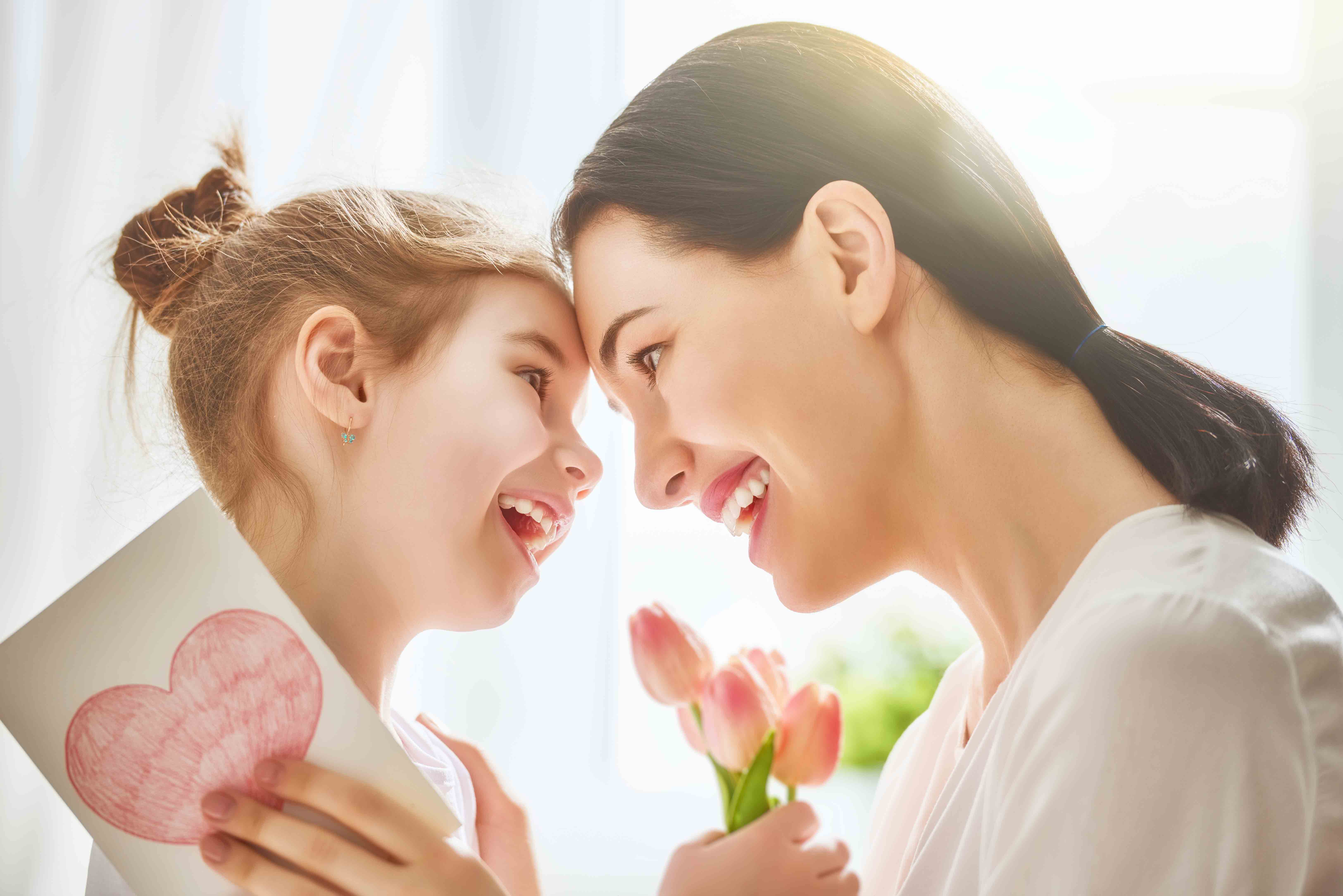Mother and daughter holding card and flowers