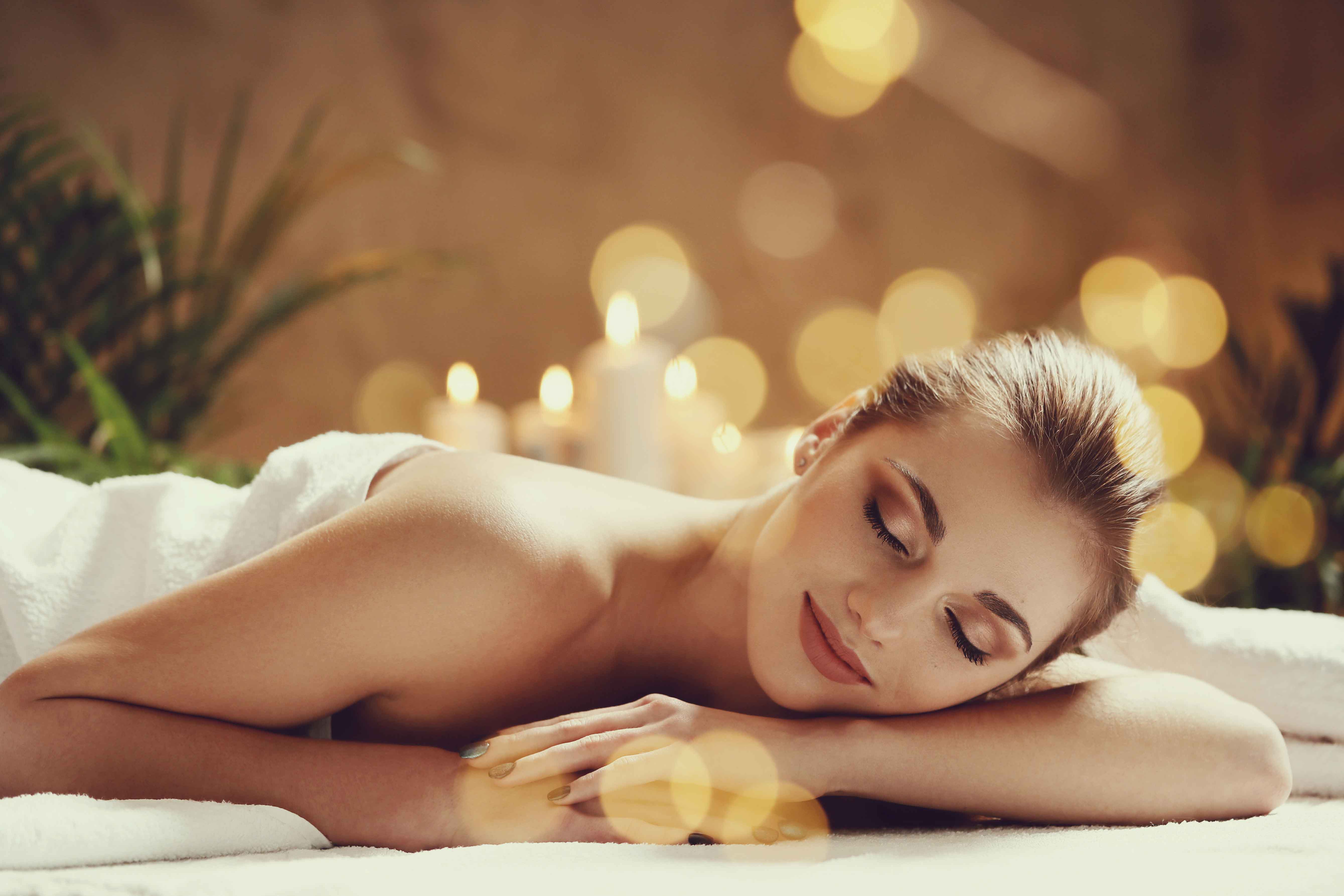 Woman wrapped in towel relaxing on spa bed